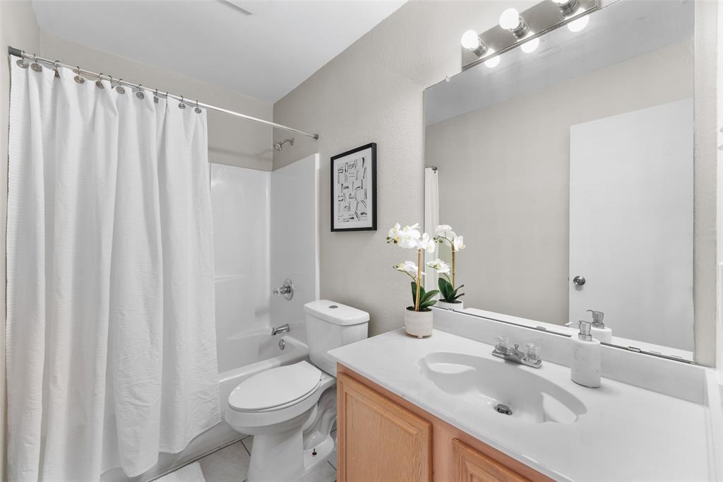 Bathroom featuring vanity, shower / bathtub combination with curtain, and light tile patterned flooring