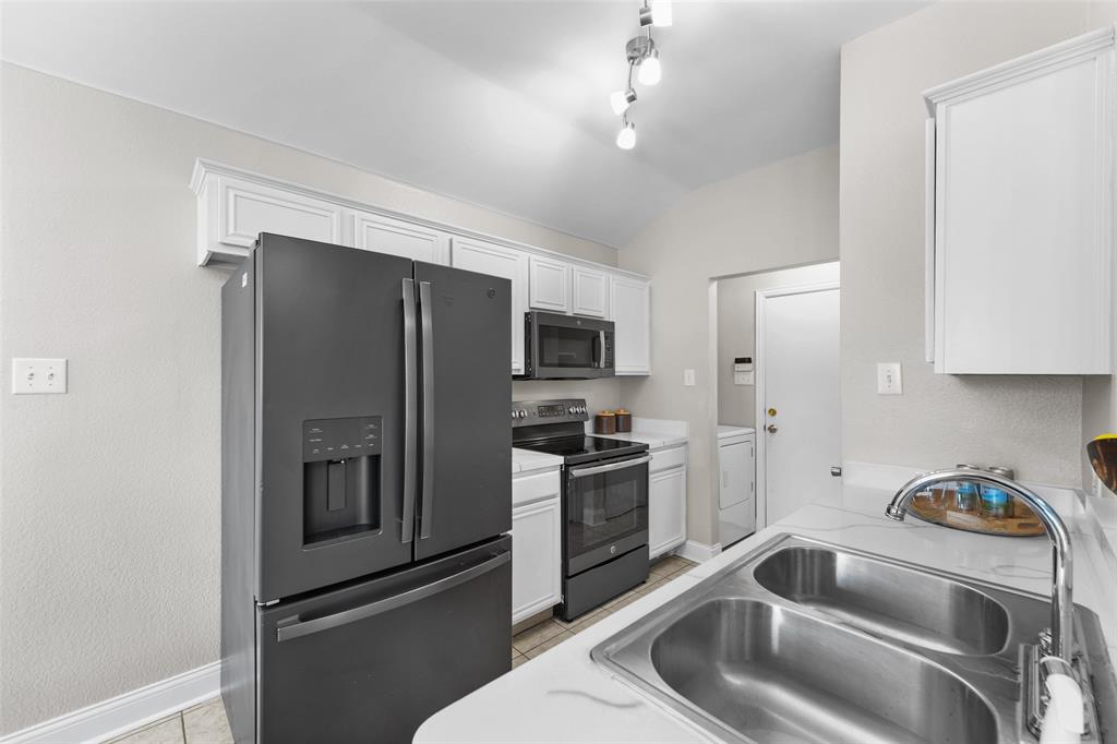 Kitchen with stainless steel appliances, white cabinets, light countertops, and light tile patterned flooring