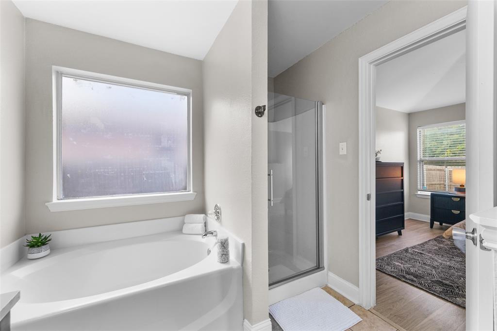 Full bath with a shower stall, a garden tub, vanity, and light wood finished floors