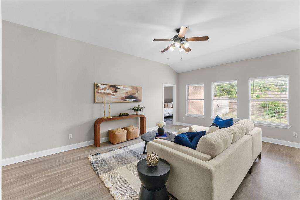 Virtually staged. Living room featuring a ceiling fan, light wood-type flooring, and vaulted ceiling