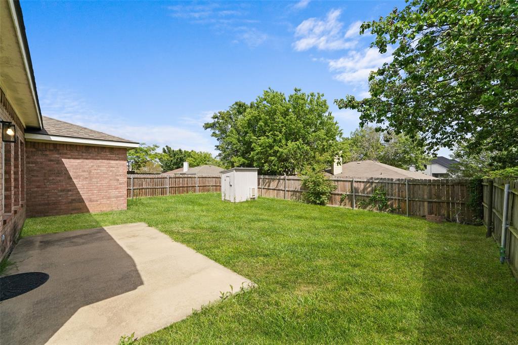 Fenced backyard featuring a storage shed and a patio area