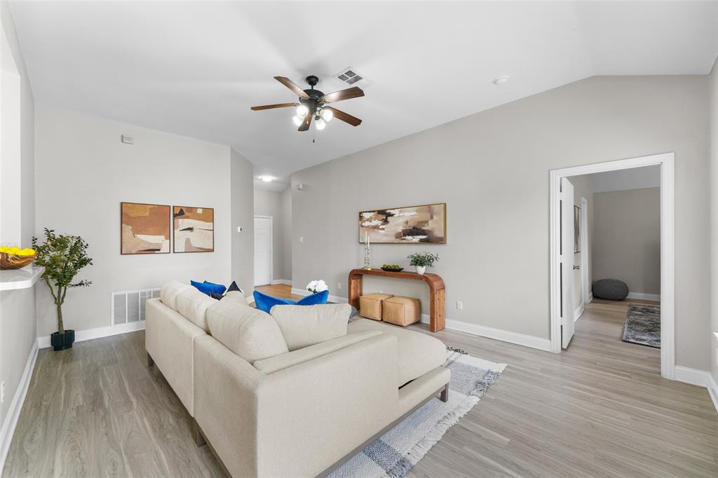 Virtually staged. Living room featuring ceiling fan, light wood-style floors, and vaulted ceiling