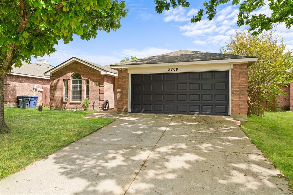 Single story home featuring a front yard, brick siding, driveway, and an attached garage