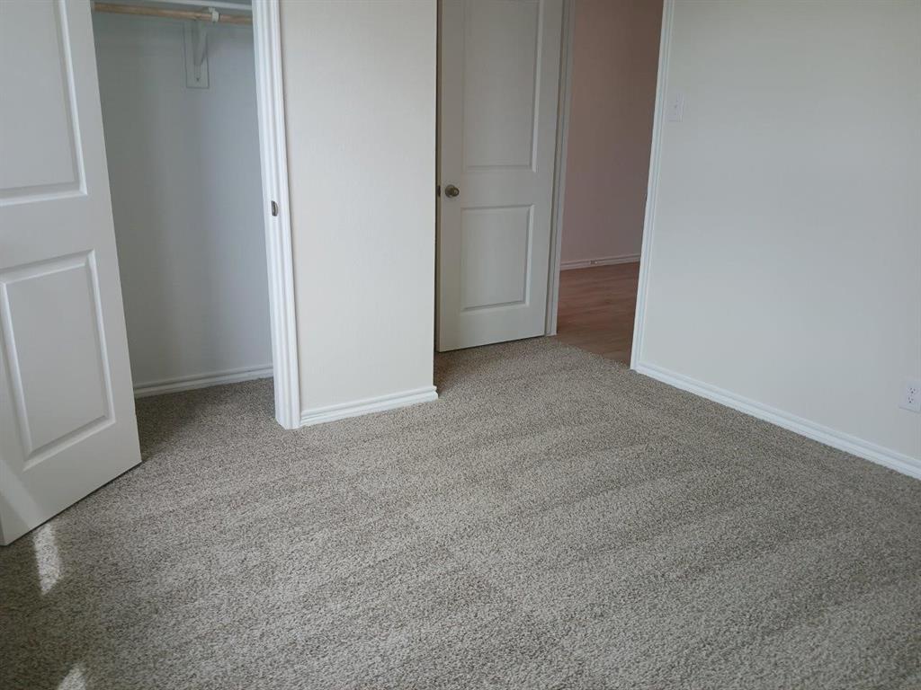 Neutral-toned carpeting extends throughout this interior space, featuring white baseboards and trim Neutral-toned carpeting extends throughout this interior space, featuring white baseboards and trim
