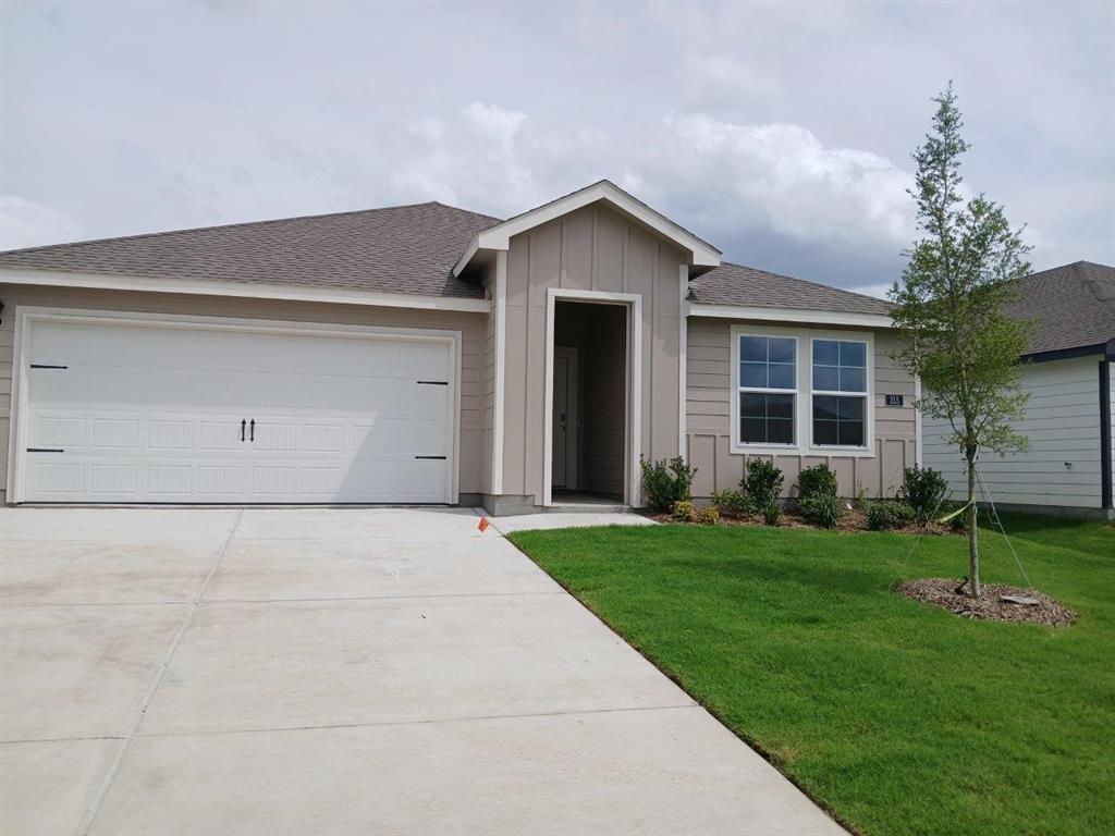 Single-story residence featuring a two-car garage with decorative hardware, a light brown facade, and a dark shingle roof Single-story residence featuring a two-car garage with decorative hardware, a light brown facade, and a dark shingle roof