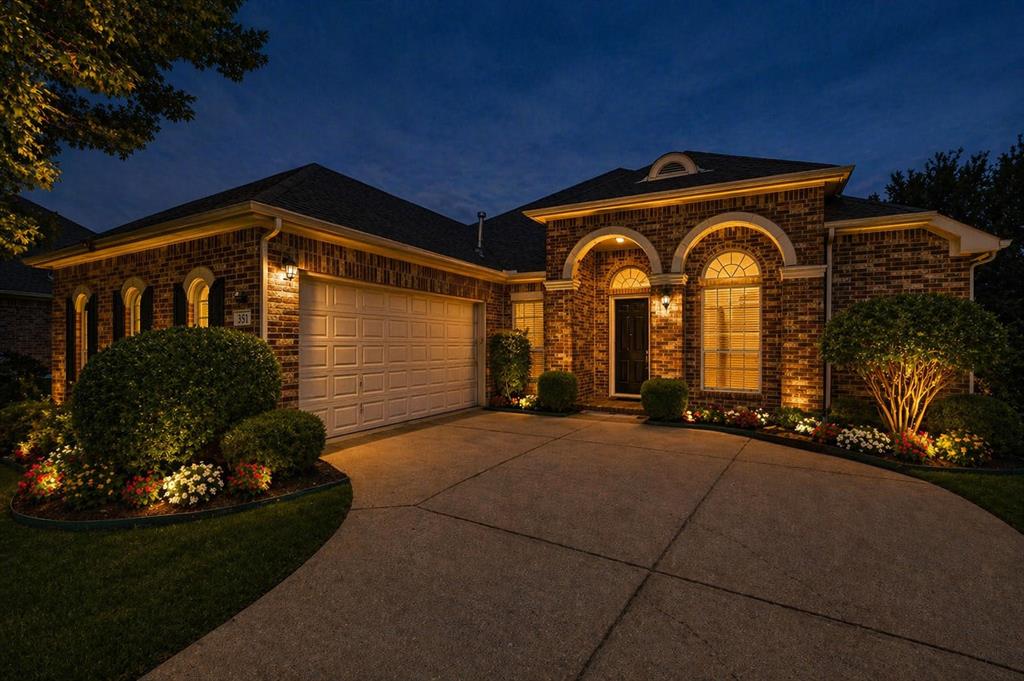Brick exterior with arched windows, an attached garage, and a concrete driveway - Virtually Staged