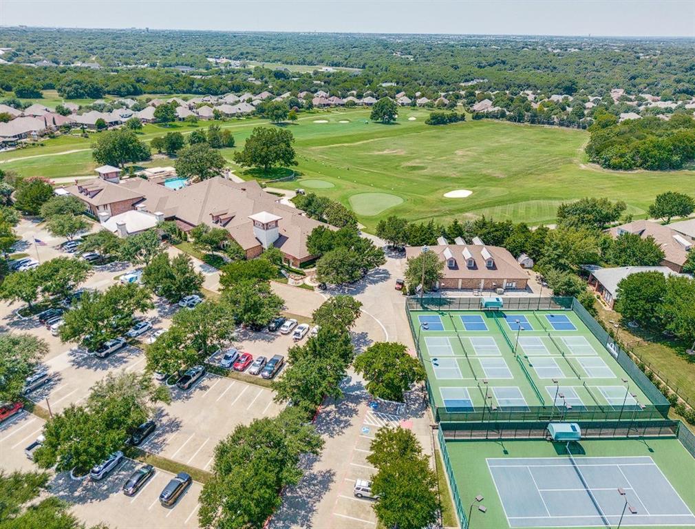 Expansive grounds featuring a golf course, multiple tennis courts, a large clubhouse, and ample paved parking