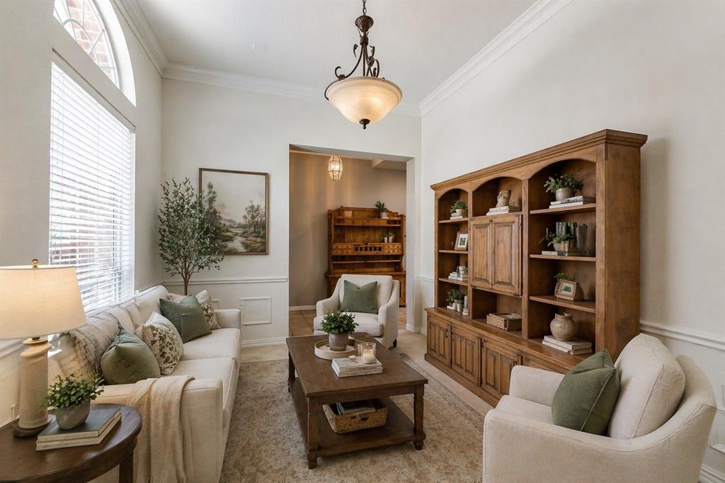 Living area featuring high ceilings with crown molding, a decorative arch window, and wainscoting - Virtually Staged