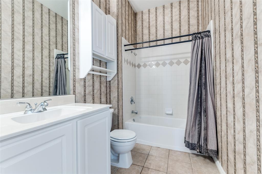 Bathroom featuring wallpapered walls, vanity, shower / bathtub combination with curtain, and light tile patterned flooring