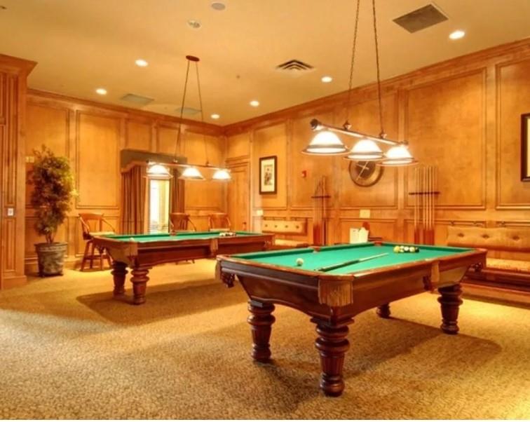Recreation room featuring two billiard tables, wood paneling with decorative trim, recessed lighting, and patterned carpeting