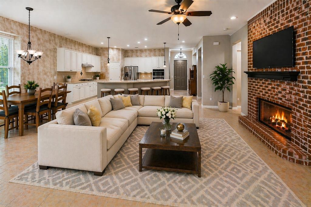 Open concept living area featuring a brick fireplace with a mantel, a ceiling fan with light fixture, and tile flooring - Virtually Staged
