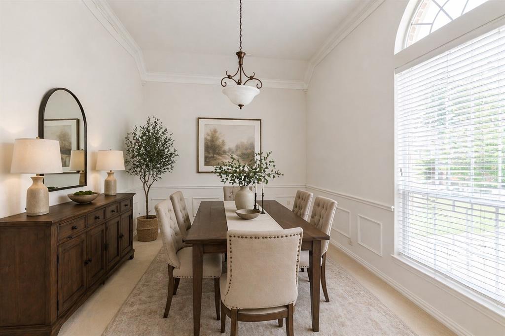 Spacious room featuring crown molding, wainscoting, and a large arched window - Virtually Staged
