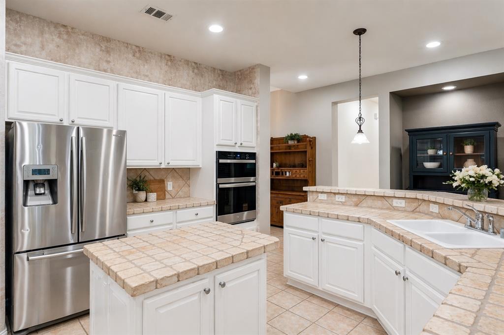Kitchen featuring white cabinetry, tile countertops, recessed lighting, stainless steel appliances, and a central island with a tiled surface