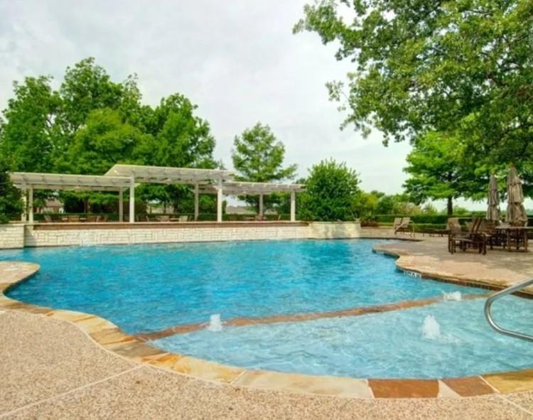 Expansive pool area featuring a blue water swimming pool with integrated spa, flagstone coping, and textured concrete decking