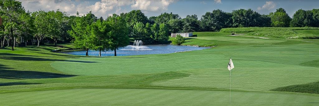Expansive green with varied terrain, mature trees, and a water feature with a fountain