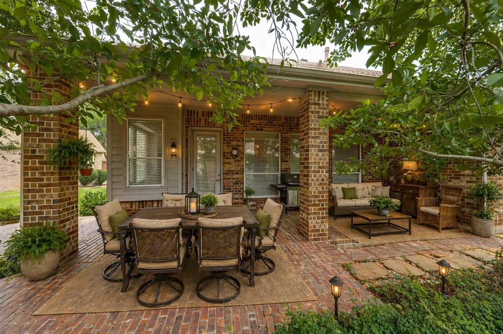 Expansive brick patio featuring a covered dining area, brick columns - Virtually Staged