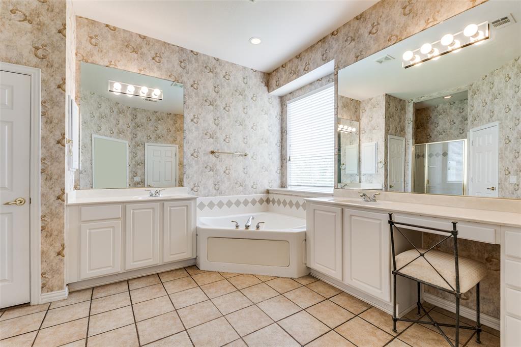 Primary bathroom featuring two vanities, light tile patterned floors, a bath, a walk-in shower, and recessed lighting