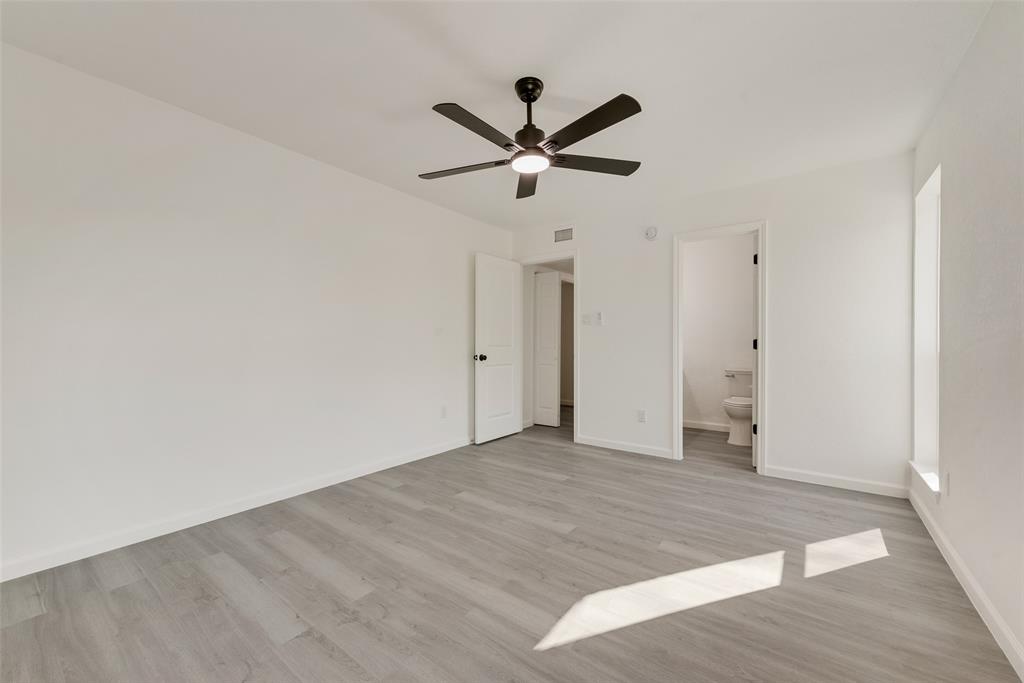 Unfurnished bedroom with ceiling fan, light wood-style flooring, and ensuite bath
