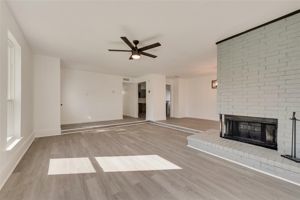 Unfurnished living room with light wood finished floors, a fireplace, and a ceiling fan Unfurnished living room with light wood finished floors, a fireplace, and a ceiling fan