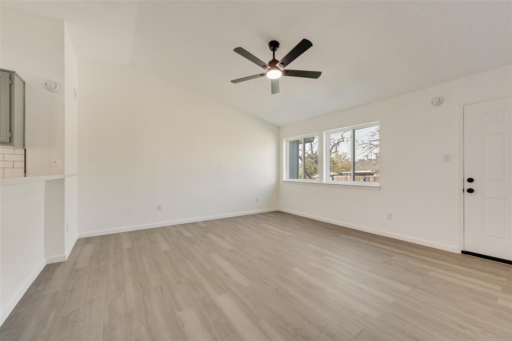 Unfurnished living room featuring light wood-style flooring, lofted ceiling, and a ceiling fan
