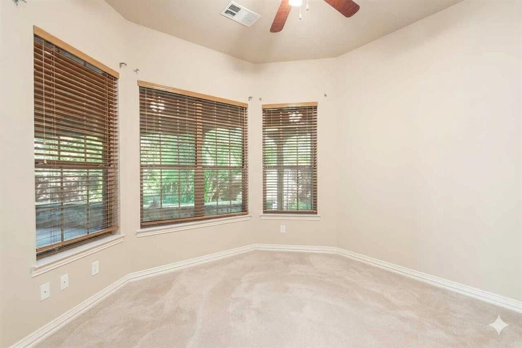 Bay window with natural wood blinds, vaulted ceiling, ceiling fan, and light-toned carpet