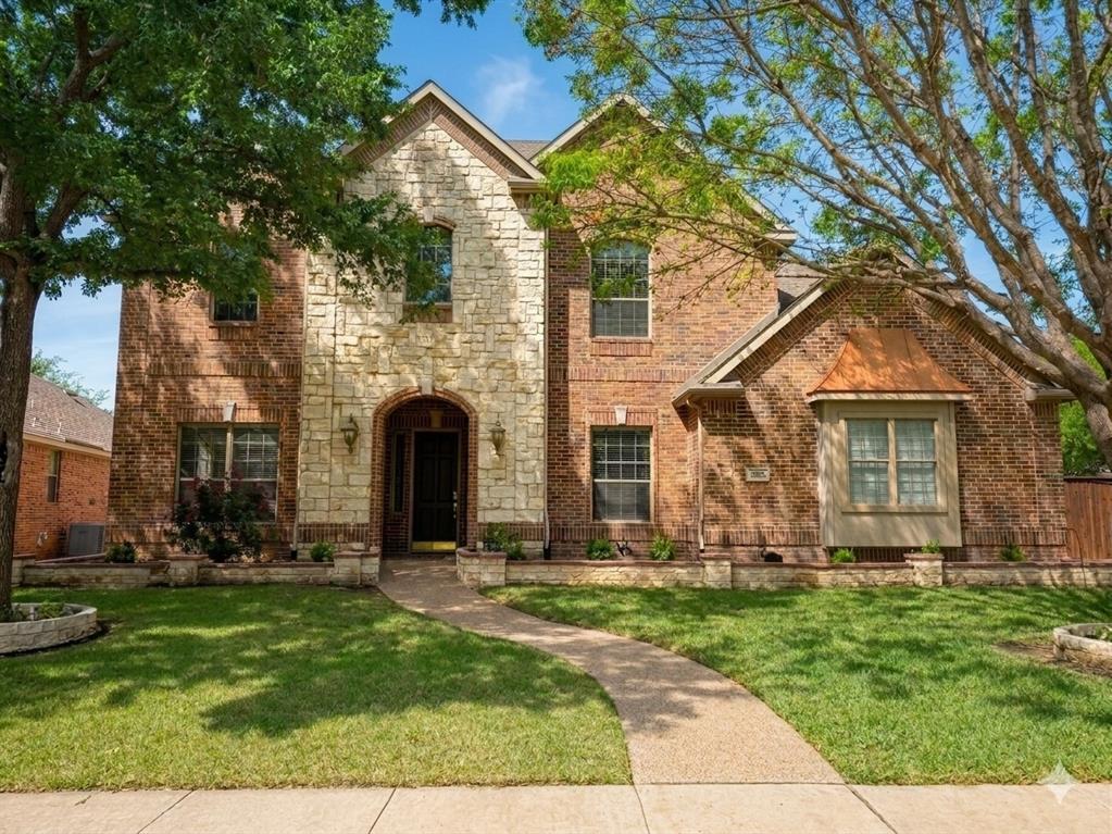 Brick and stone exterior with an arched entryway, gabled rooflines, and a bay window featuring a copper-toned roof accent