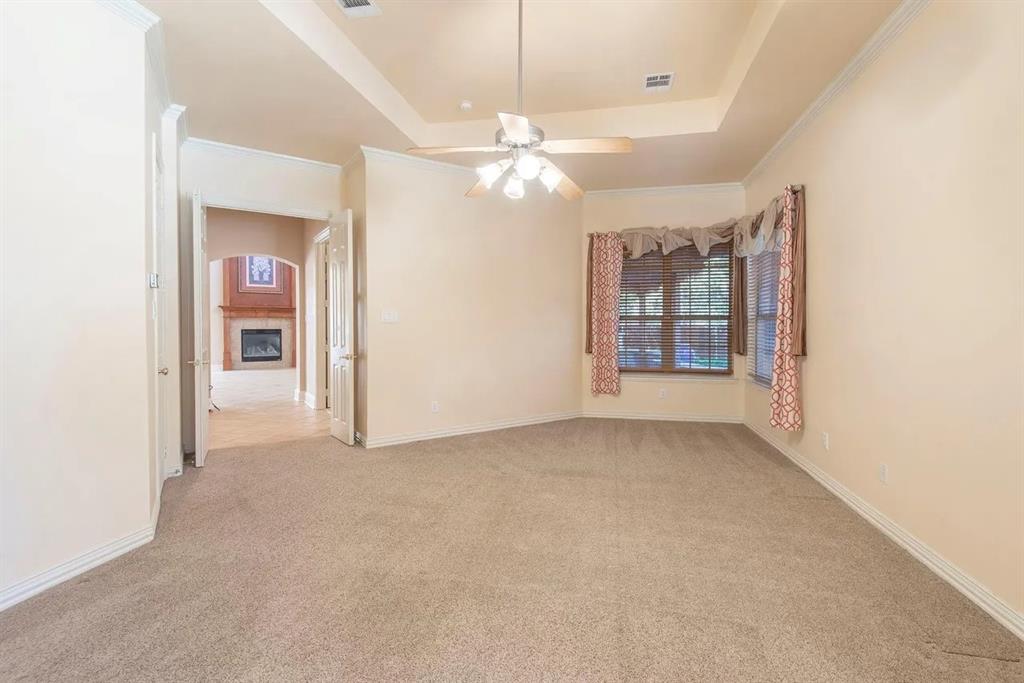 Carpeted room featuring a ceiling fan, tray ceiling, bay window, and arched doorway