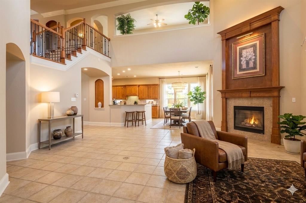 Two-story living area featuring a prominent fireplace with a wood mantle surround, tile hearth, and an open-concept layout
