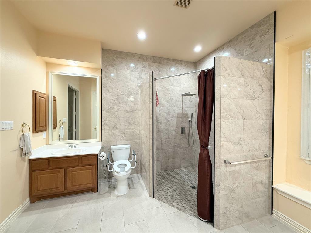 Spacious bathroom featuring a large walk-in shower with tiled walls and a rain showerhead