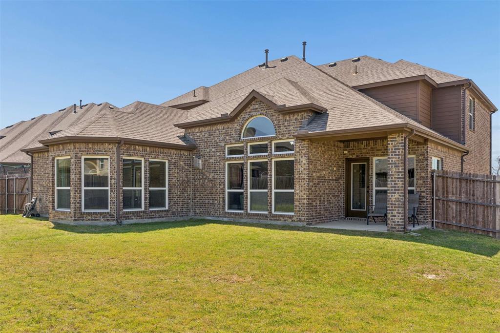 Rear view of property with a fenced backyard, a patio, brick siding, and a shingled roof