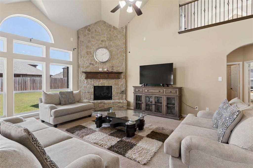 Carpeted living area featuring arched walkways, lofted ceiling, a fireplace, and ceiling fan