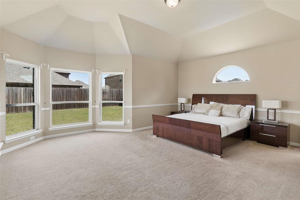 Bedroom featuring light colored carpet, multiple windows, and vaulted ceiling