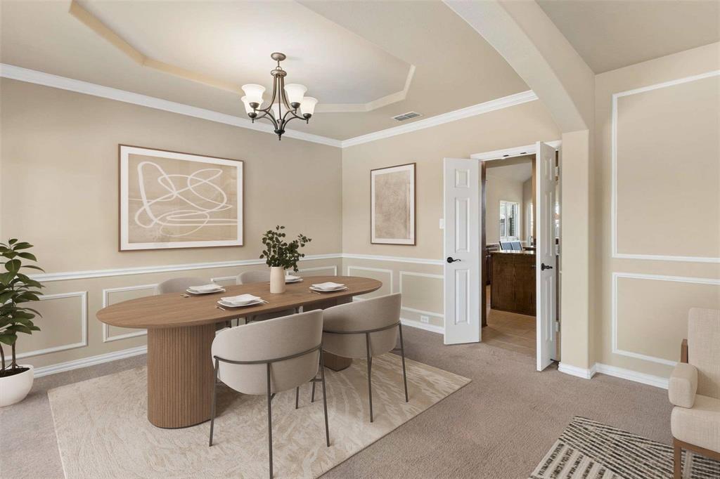 Formal dining area with tray ceiling, crown molding, and wainscoting