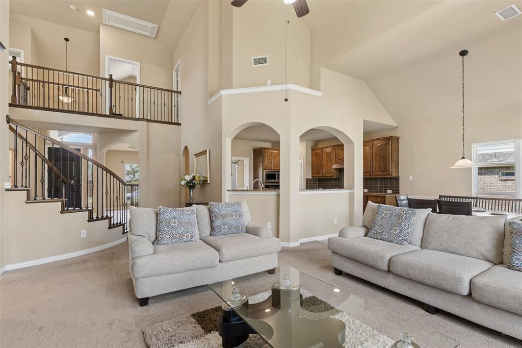 Living room with carpet floors, a high ceiling, arched walkways, and ceiling fan