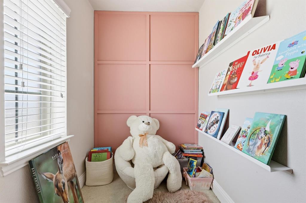 Reading nook off bedroom #3 w/ paneled accent wall, white window blinds, and built-in floating book shelves