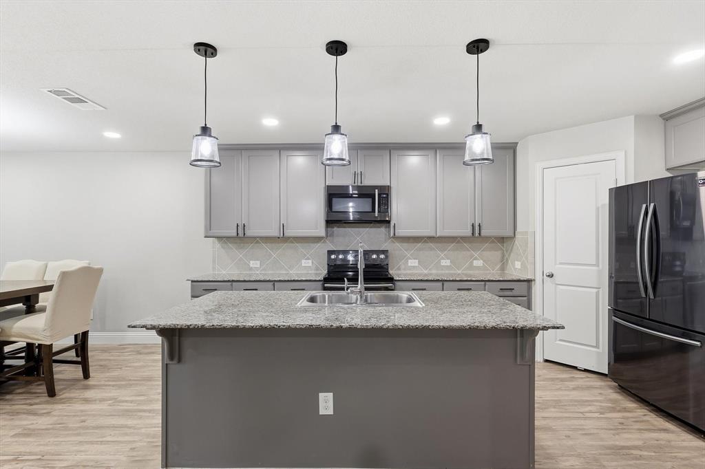 Kitchen island featuring a double basin sink and a granite countertop
