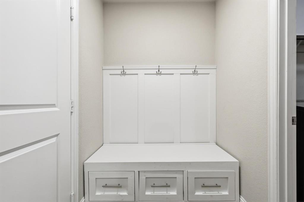 Built-in mudroom bench with three storage drawers, integrated coat hooks, and crisp white paneling