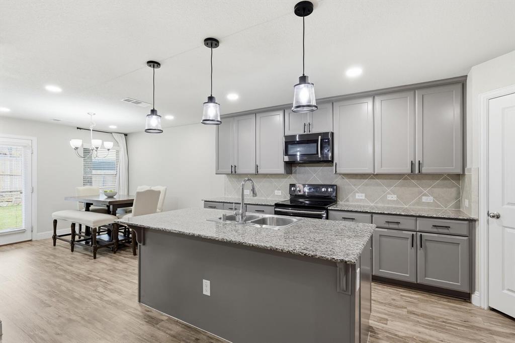 Modern kitchen featuring a central island with a double basin sink and pendant lighting