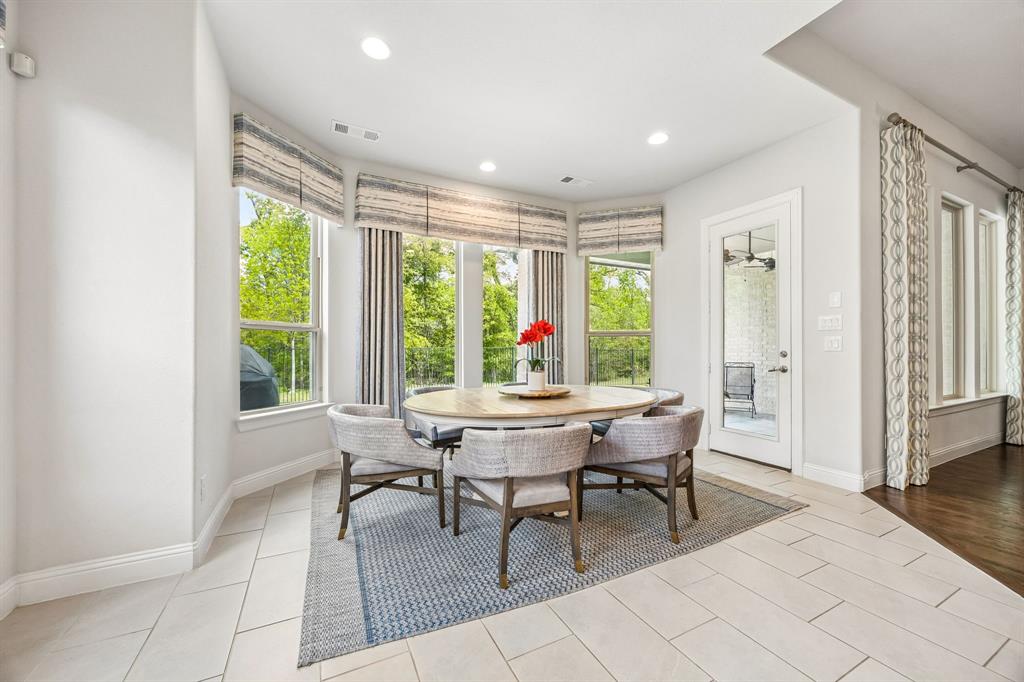 Spacious breakfast room featuring a stunning wall of panoramic bay windows overlooking the grassy yard and lush greenbelt.