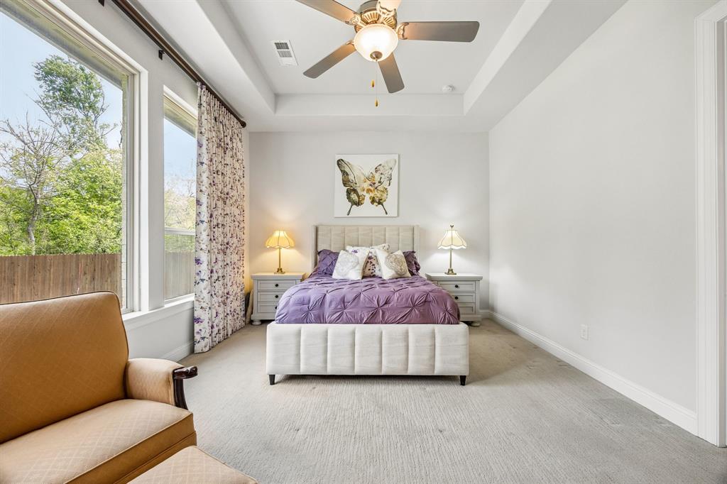 Elegant tray ceiling adds architectural depth and height to the primary suite. Towering windows flood the room with natural light while offering scenic backyard and greenbelt views.