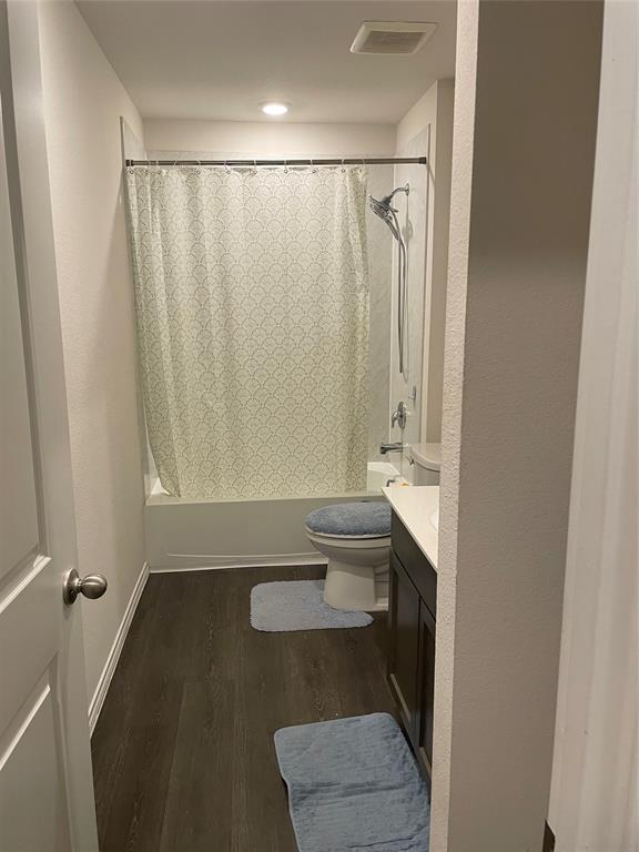 Full bath featuring vanity, dark wood finished floors, and shower / tub combo with curtain