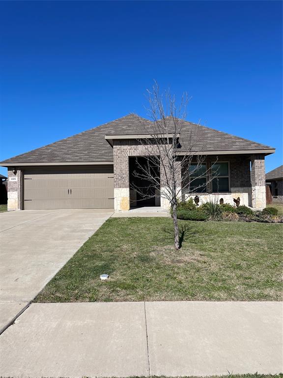 View of front of house featuring driveway, brick siding, an attached garage, stone siding, and a shingled roof