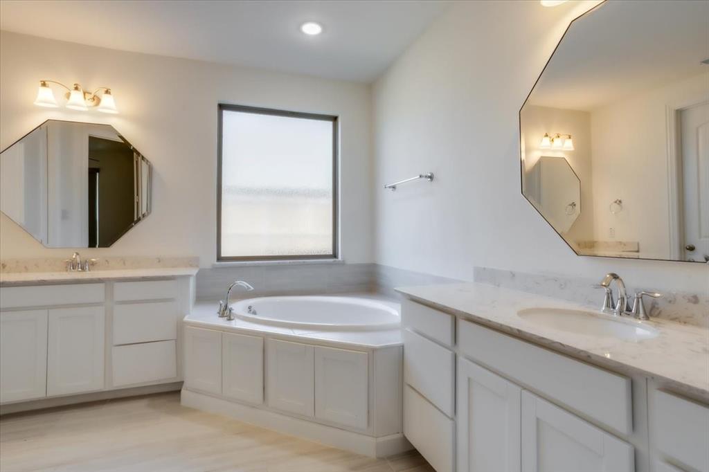 Primary bathroom with dual vanities and a garden tub.