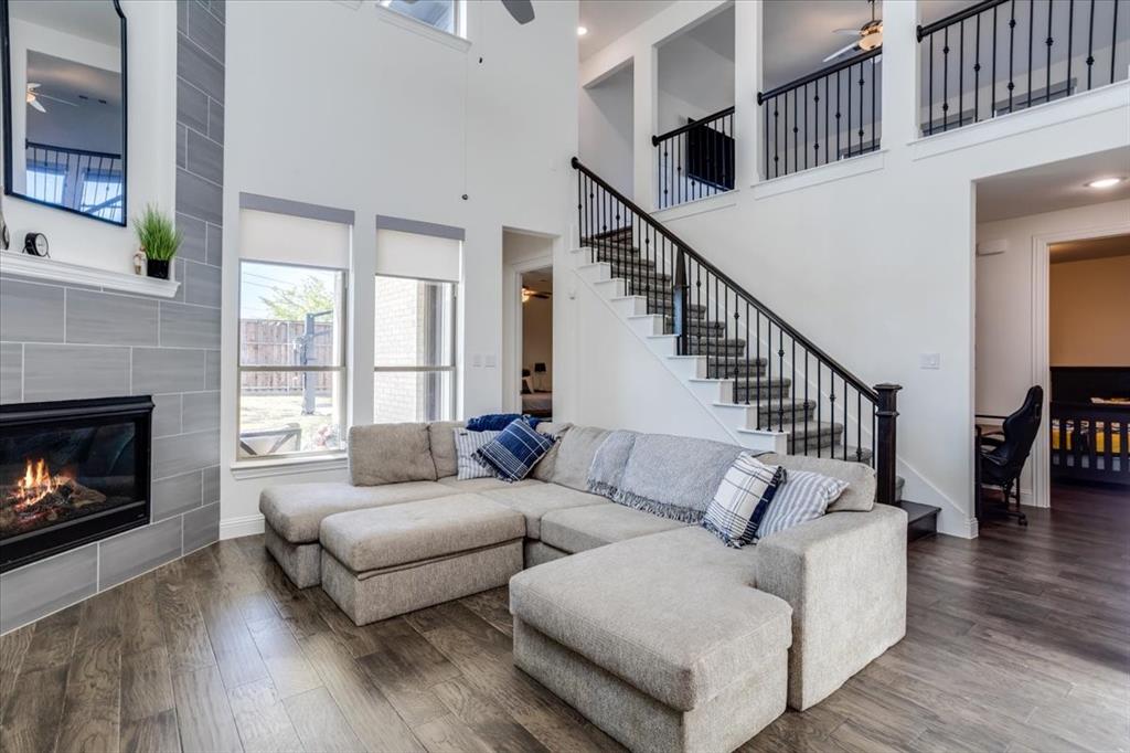 Soaring ceilings at the family room anchored by a fireplace with floor to ceiling tile surround.