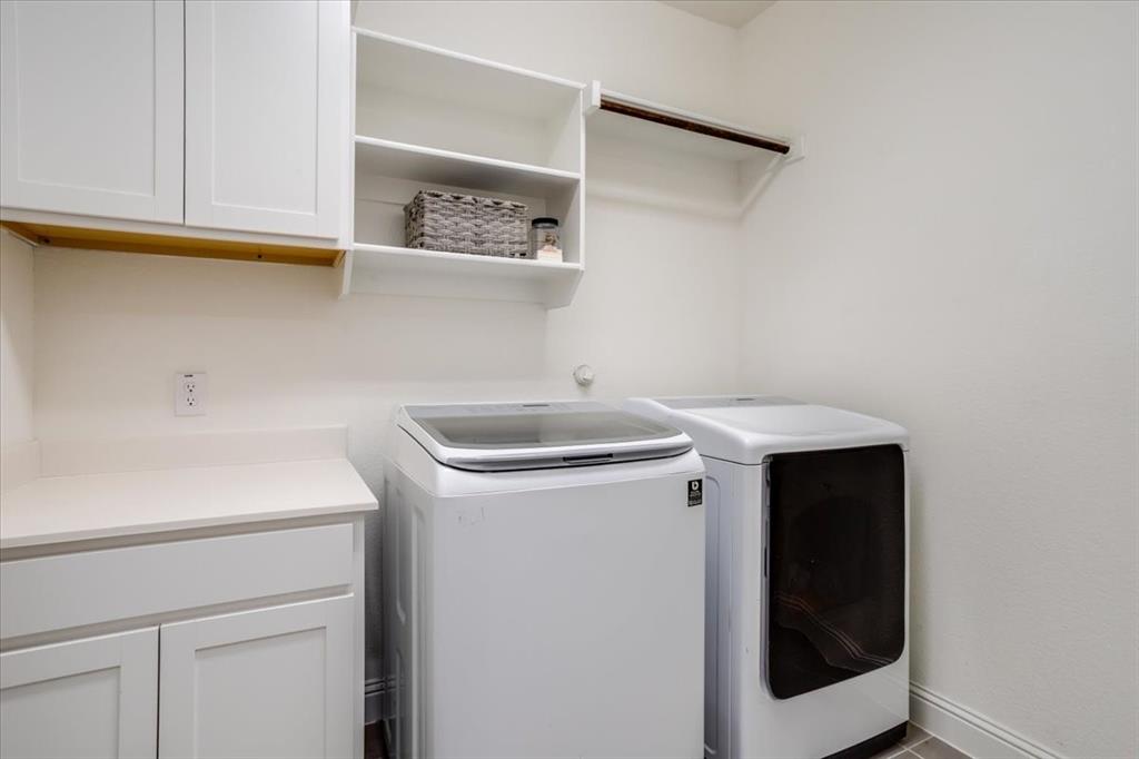 Laundry room with full size washer/dryer area + upper and lower cabinetry.