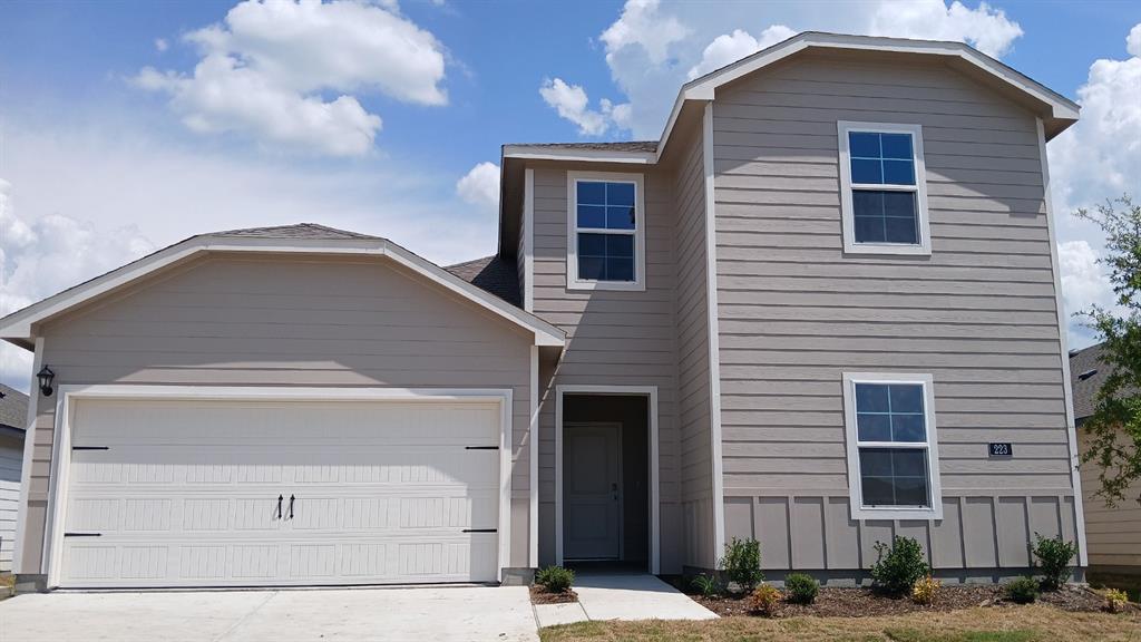 Two-story residence featuring light beige siding and a prominent two-car garage with decorative hardware