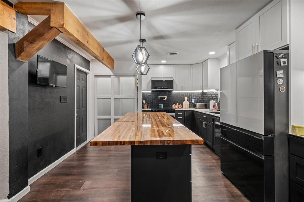 The kitchen features a spacious butcher block island, dark wood flooring, and modern pendant lighting