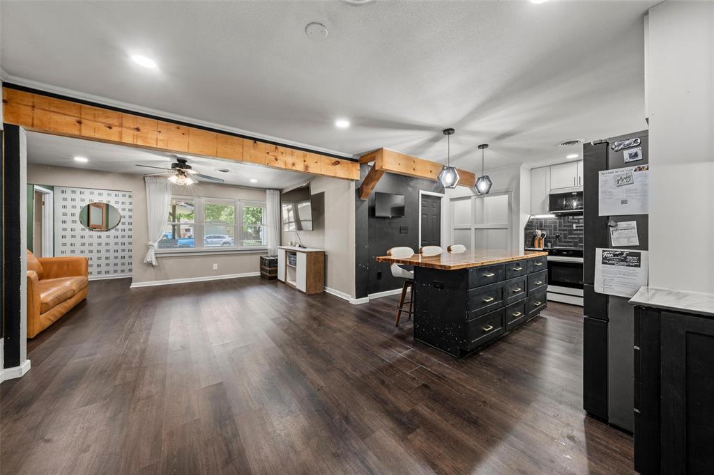 Dual tone kitchen featuring open floor plan, decorative light fixtures, a kitchen breakfast bar, freestanding refrigerator, and two tone cabinets Dual tone kitchen featuring open floor plan, decorative light fixtures, a kitchen breakfast bar, freestanding refrigerator, and two tone cabinets