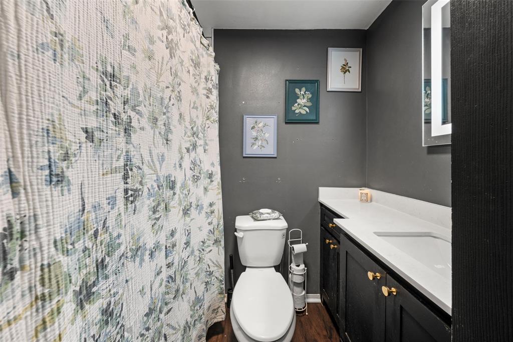 Full bath with vanity, curtained shower, and dark wood-type flooring