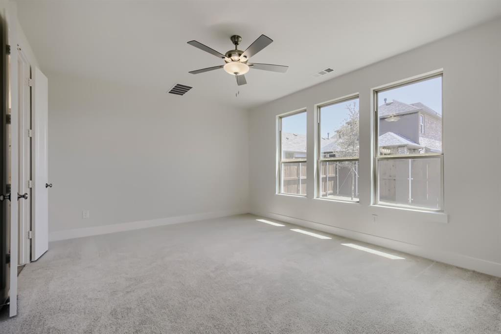 Spacious room featuring three large windows, light gray carpeting, and a ceiling fan with integrated lighting